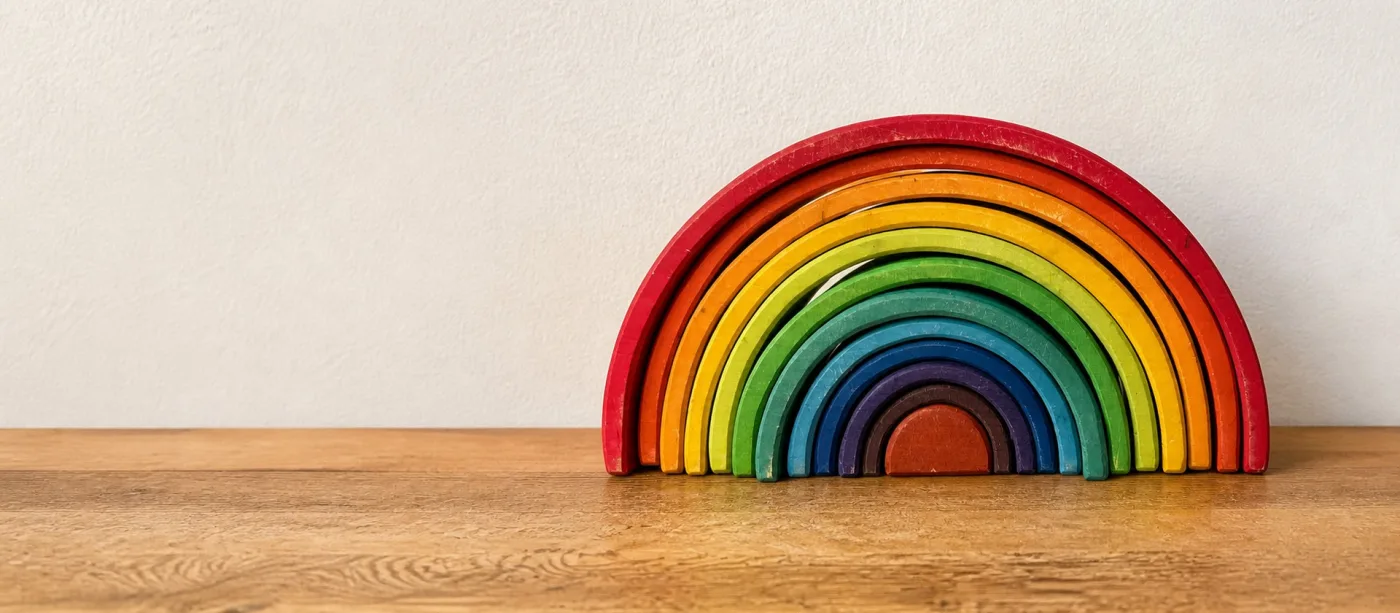 Bunter Holzregenbogen zum Stapeln auf einem Regalbrett aus Kiefer.